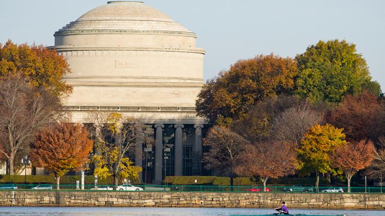 alt="The MIT Dome and Killian Court seen from across the Charles River in autumn, with fall foliage"