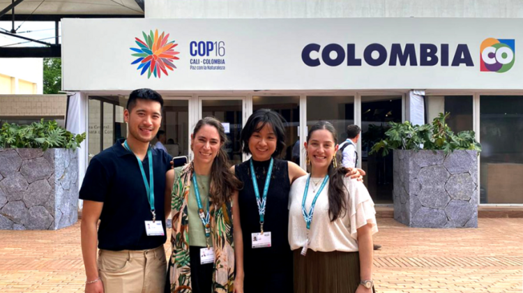 Four people wearing lanyards pose outside