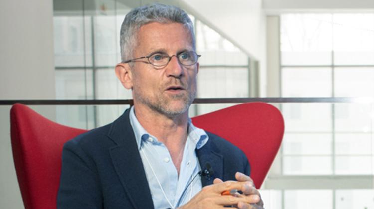 Photograph of Carlo Ratti sitting in a high-backed bright red chair