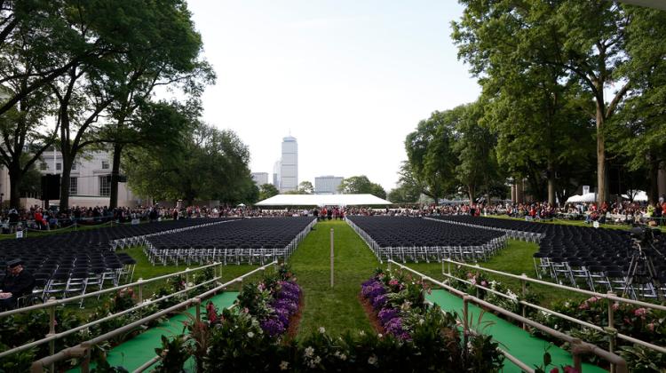 Photo of MIT's Killian Court, facing Boston, featuring hundreds of empty seats meant for new graduates, while spectators stand in the background