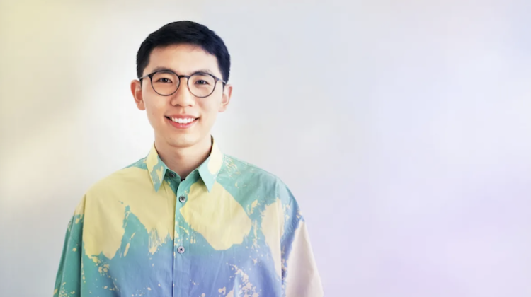 Portrait of Chen Chu, wearing a green and yellow button up shirt and with a pastel and gray background.