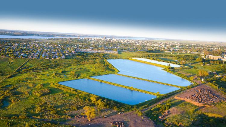 An isometric view of a sewage treatment plant in Rio Grande do Sul Province, in the distant background one can see housing separated by green space and then three water fields used for the treatment of waste water.