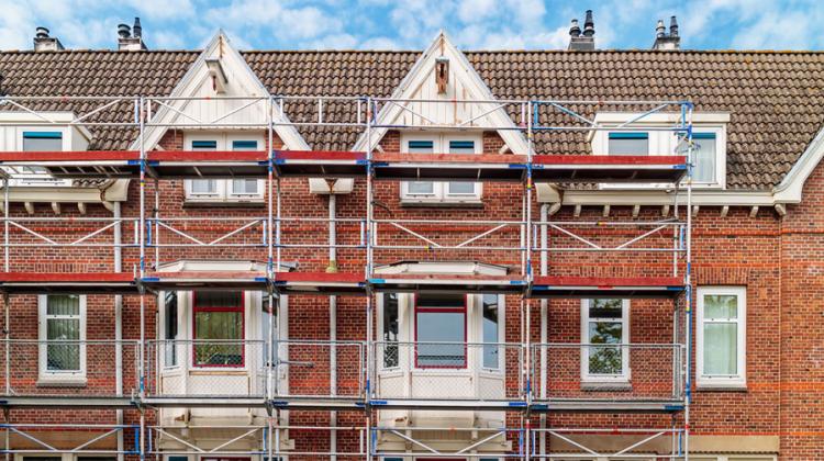 Scaffolding sits in front of red brick rowhouses in Amsterdam being renovated