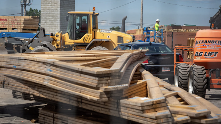 Roofing trusses are flanked by construction vehicles and a concrete block exit stairwell in the background