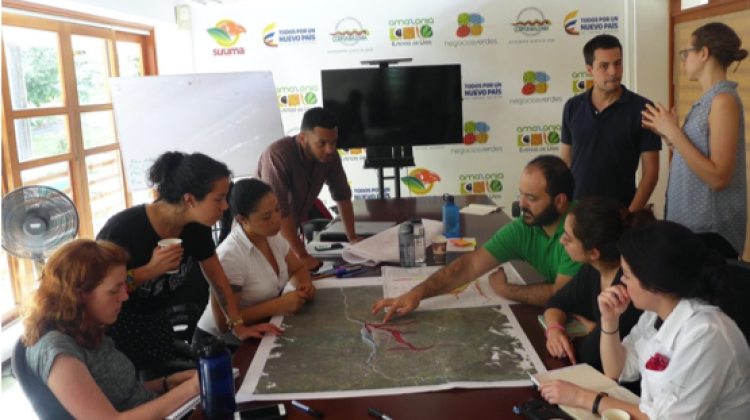 A group of individuals gathers around a map at a workshop in Columbia