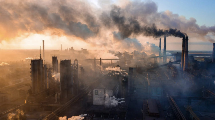 Landscape image shows an urban area to the left and smoke towers on the right, air pollution is picked out by the rising sun