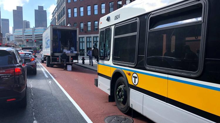 A bus, in a designated bus lane, is stopped because an illegally parked delivery vehicle