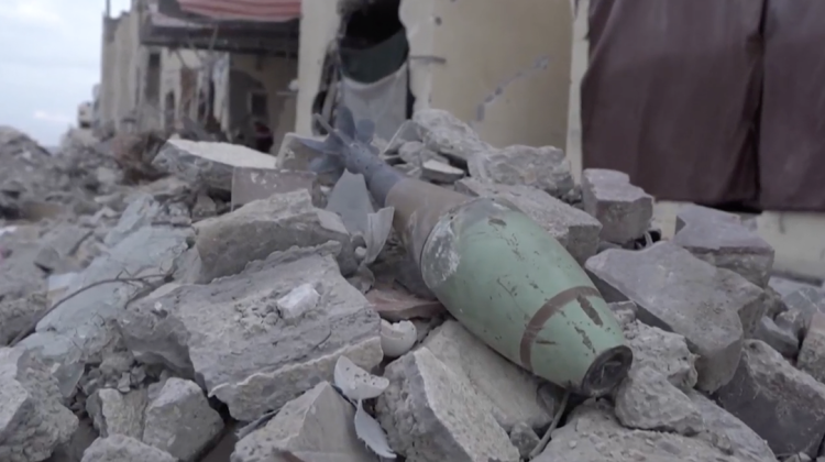 An unexploded bomb lies atop rubble