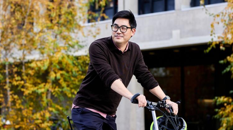 David Hsu rides a bike, which is half-seen, while outside.