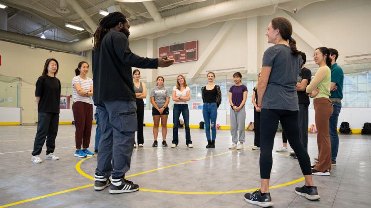 Instructor and students standing in a circle in a gymnasium