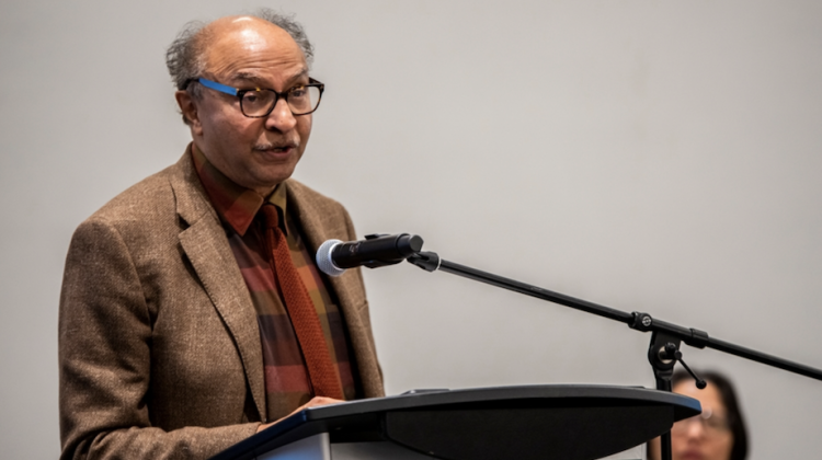 Image of Bish Sanyal standing in front of a podium delivering his speech for the ACSP Distinguished Educator Award