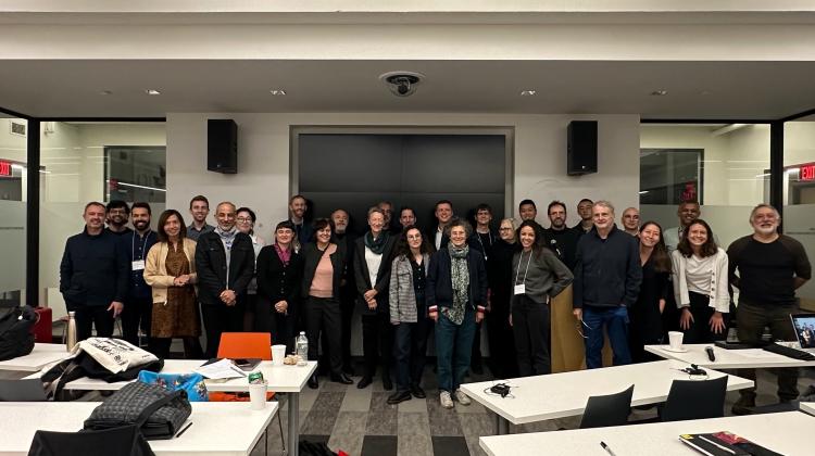 Group photo of participants of Urban Ground Floors, folks are assembled in front of the display of 9-255, desks/tables can be seen in the foreground